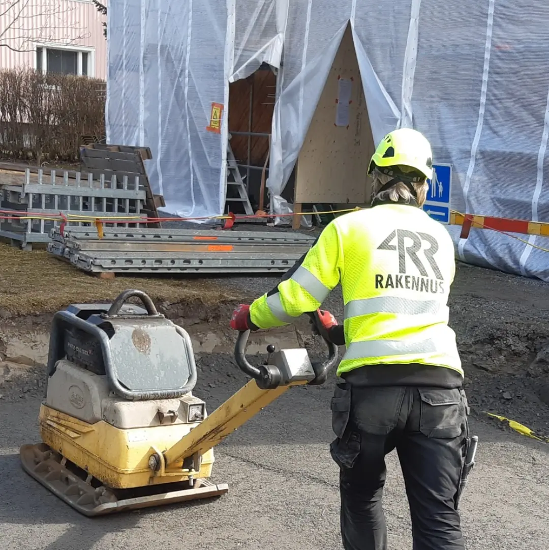 Työntekijä tiivistää maata tärylevyllä työmaalla